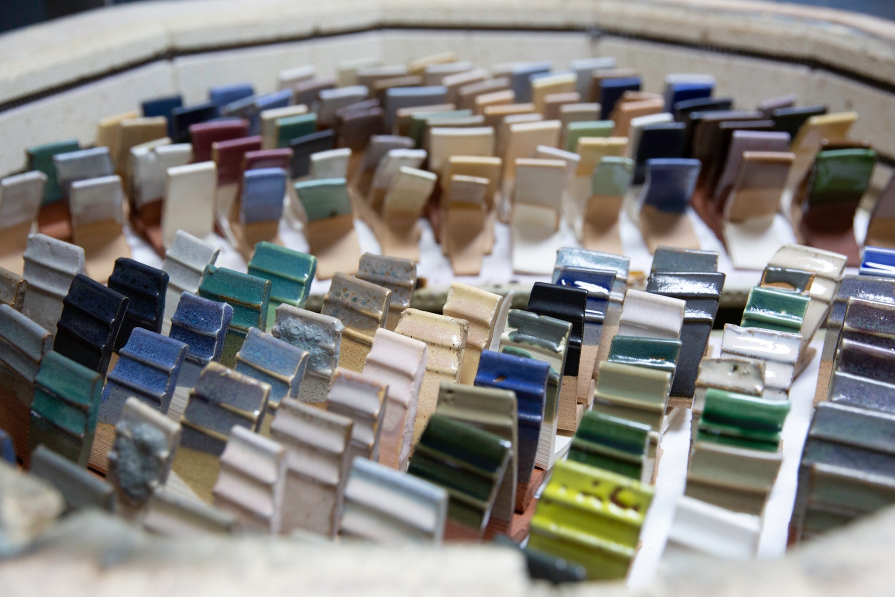 Collection of small ceramic test tiles in various colors arranged in a circular pattern.