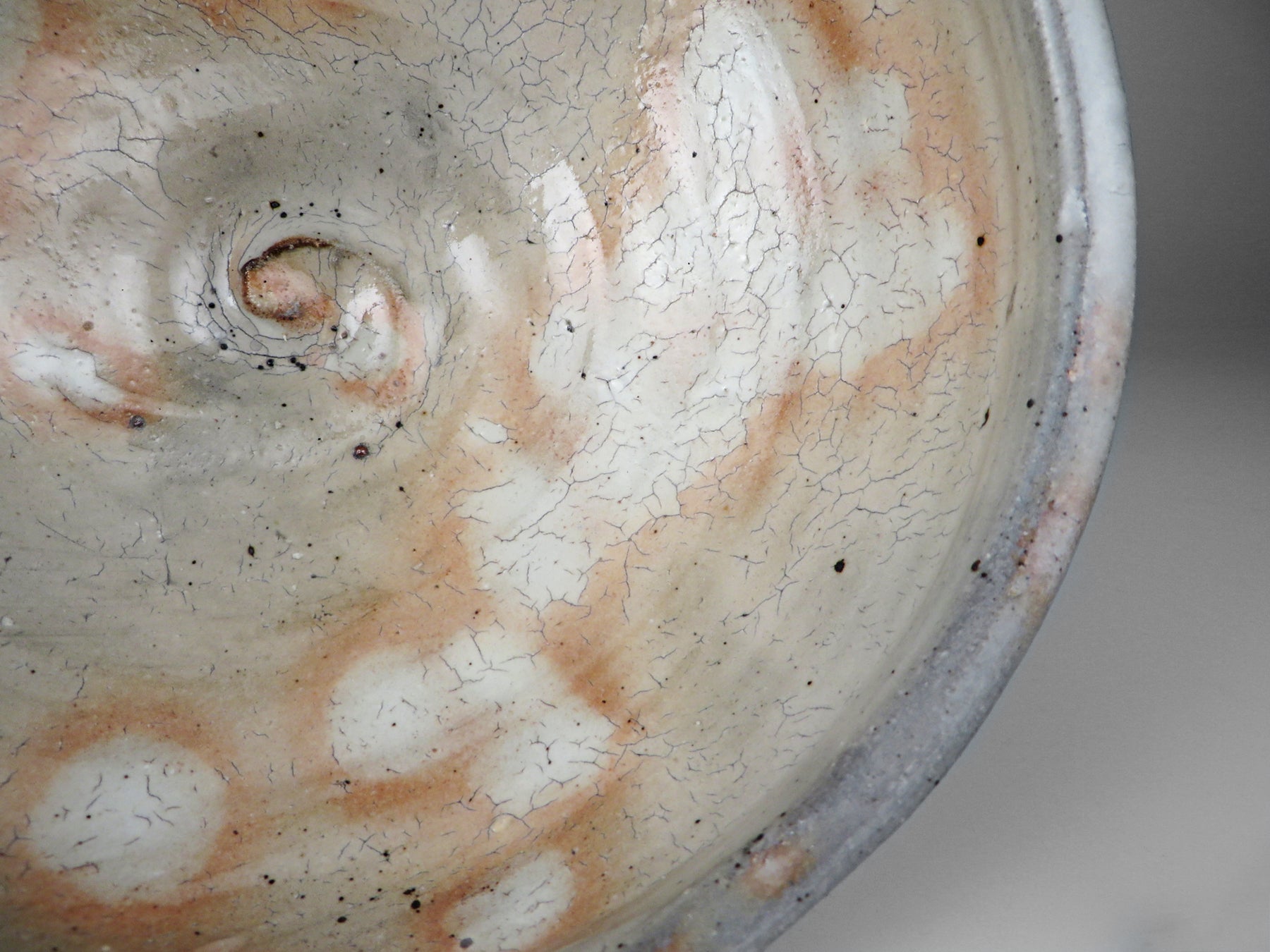 Close-up of a ceramic pot with textured surface with white and rust colored spots