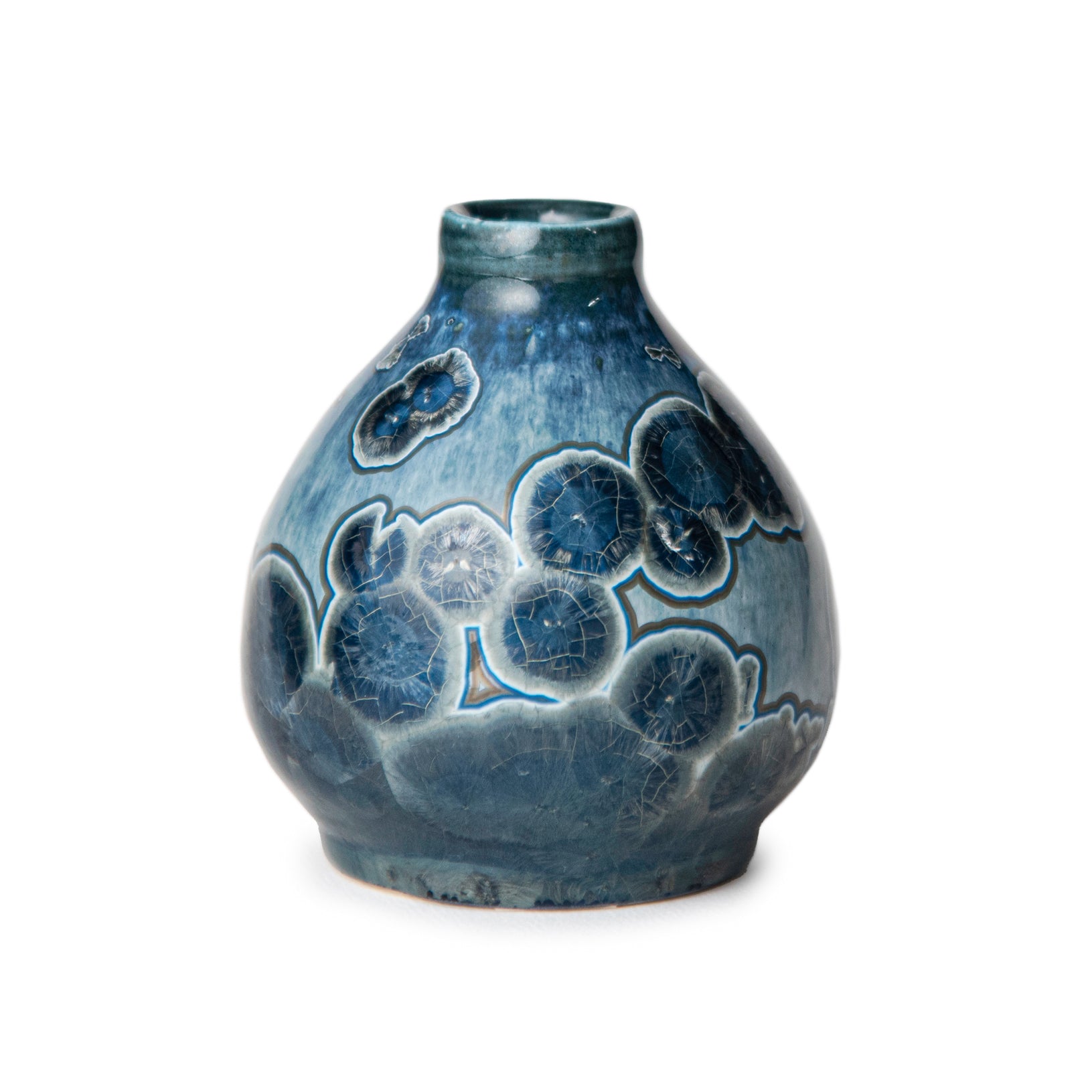 Blue ceramic vase with a circular crystalline  patterns on a white background. artist john britt
