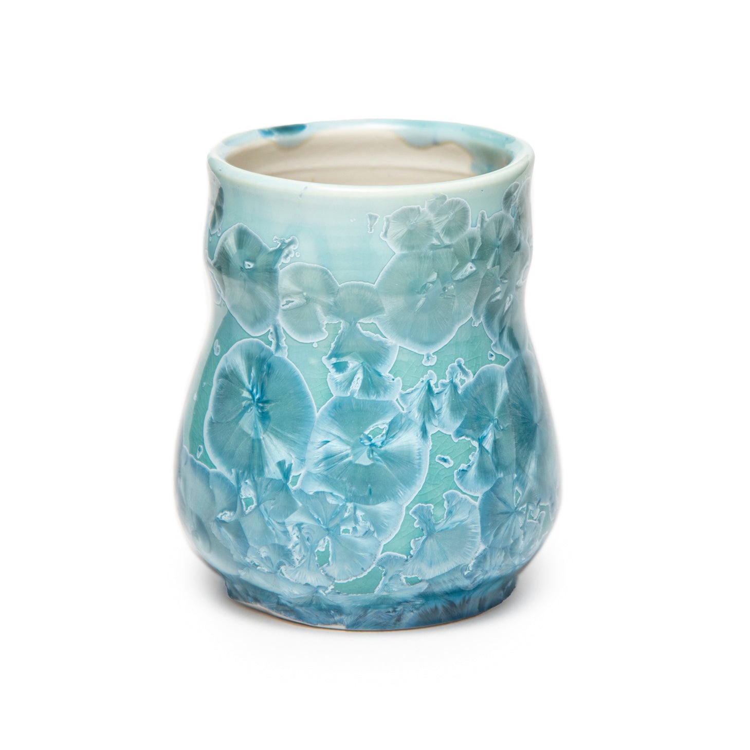A light blue and iridescent crystalline glazed cup by artist John Britt against a white background