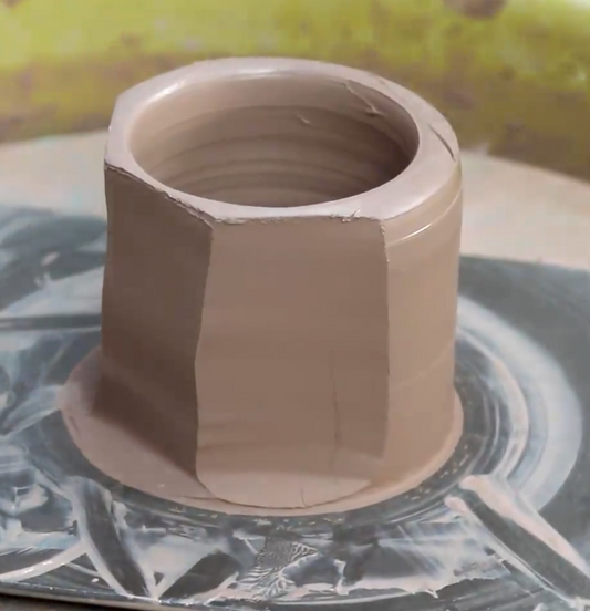 A faceted wet clay pot on a pottery wheel 